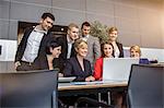 Businesswoman and office team looking at laptop