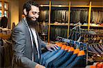 Tailor looking at business jacket display in men's clothes shop