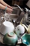 Woman washing dishes, cups on foreground