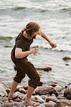 Young man throwing stones on beach, Gotland, Sweden
