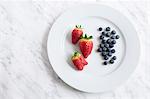 Strawberries and blueberries on plate, studio shot