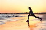 Woman exercising on beach at sunset