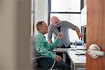 Two men in an office looking at a computer screen.