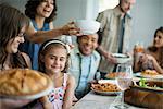 A family gathering for a meal. Adults and children around a table.