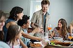 A family gathering for a meal. Adults and children around a table.