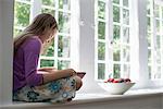 Girl sitting by a window, reading a book.