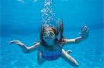 A child swimming under water in a swimming pool.