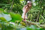 A girl playing at a pond in a forest.