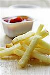 Traditional potatoes French fries with salt on wooden background