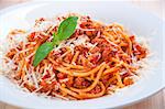 spaghetti bolognese on white plate with tomato sauce and basil leaves