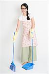 Full length Asian Chinese female housekeeping, sweeping floor with broom on plain background.