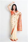 Full length Asian Indian female in dancing pose on plain background.