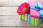 Purple gerbera flower in gift box on wooden table with copy space