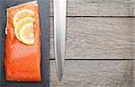 Fresh salmon fish with lemon and japan knife on wooden table with copy space