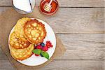 Pancakes with raspberry, blueberry, milk and honey syrup. On wooden table with copy space