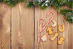 Christmas fir tree with snow, candy cane and gingerbread cookies on rustic wooden board with copy space