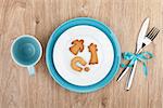 Kitchen utensils over wooden table with cookies on plate