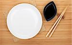 Empty plate, sushi chopsticks and soy sauce on bamboo table