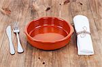 plate, knife and fork at napkin on wooden background