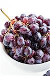 Branch of purple grape in a bowl on white background