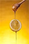 Honey flowing on lemon slice, studio shot over yellow background