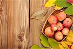 Autumn leaves and apples over wood background with copy space