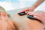 Close-up mid section of a young woman receiving stone massage at health farm