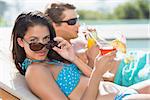 Side view of a young couple with drinks by swimming pool