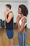 Fit couple standing with hands together at the gym