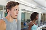 Fit man running on treadmill listening to music at the gym