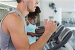 Fit man and woman running on treadmill at the gym