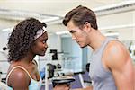 Fit couple lifting dumbbells together at the gym