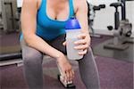 Fit brunette holding sports bottle at the gym