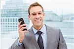 Portrait of smart young businessman using mobile phone in office