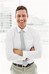 Portrait of happy young businessman with arms crossed in office