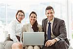 Three young business people using laptop in office