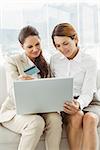 Happy young businesswomen doing online shopping through laptop and credit card