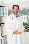 Portrait of confident smiling male doctor with reports at the medical office