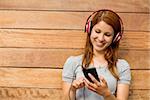 Girl listening music with headphones while sending message in the city