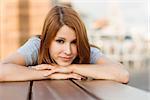 Smiling pretty redhead lying on bench on a sunny day in the city