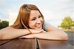 Smiling casual redhead lying on bench in the city