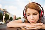 Woman listening with headphones to music with eyes closed in the city