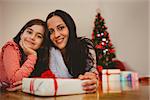 Festive mother and daughter smiling at camera at home in the living room