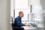 A man working in an office at a desk using a computer mouse. Focusing on a task.