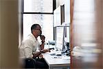 A man working in an office seated at a desk. Looking at a computer screen.