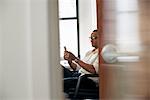 A man sitting in an office, checking his smart phone.