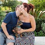 A couple playing with their small dog in the park.