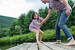 A couple trying to pull each other into the water off a jetty