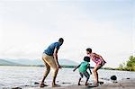 A family, mother, father and son playing on the shores of a lake.