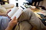 Man sitting on sofa reading a book.